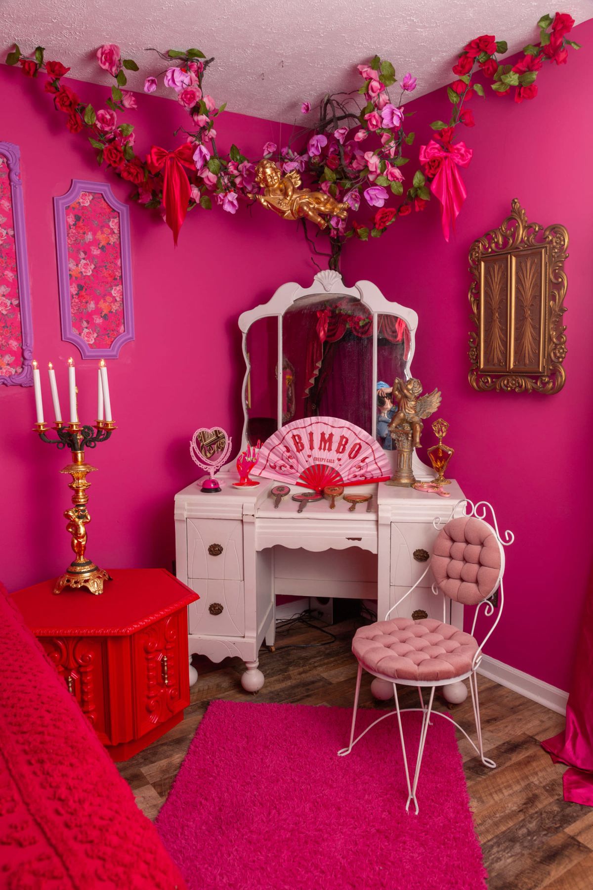 Pink room with white vanity, red table and floral accents