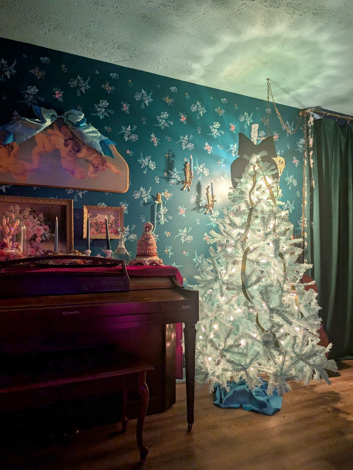 The scene features a decorated Christmas tree with white lights in a room with a teal wall adorned with snowflake patterns and vintage decor.