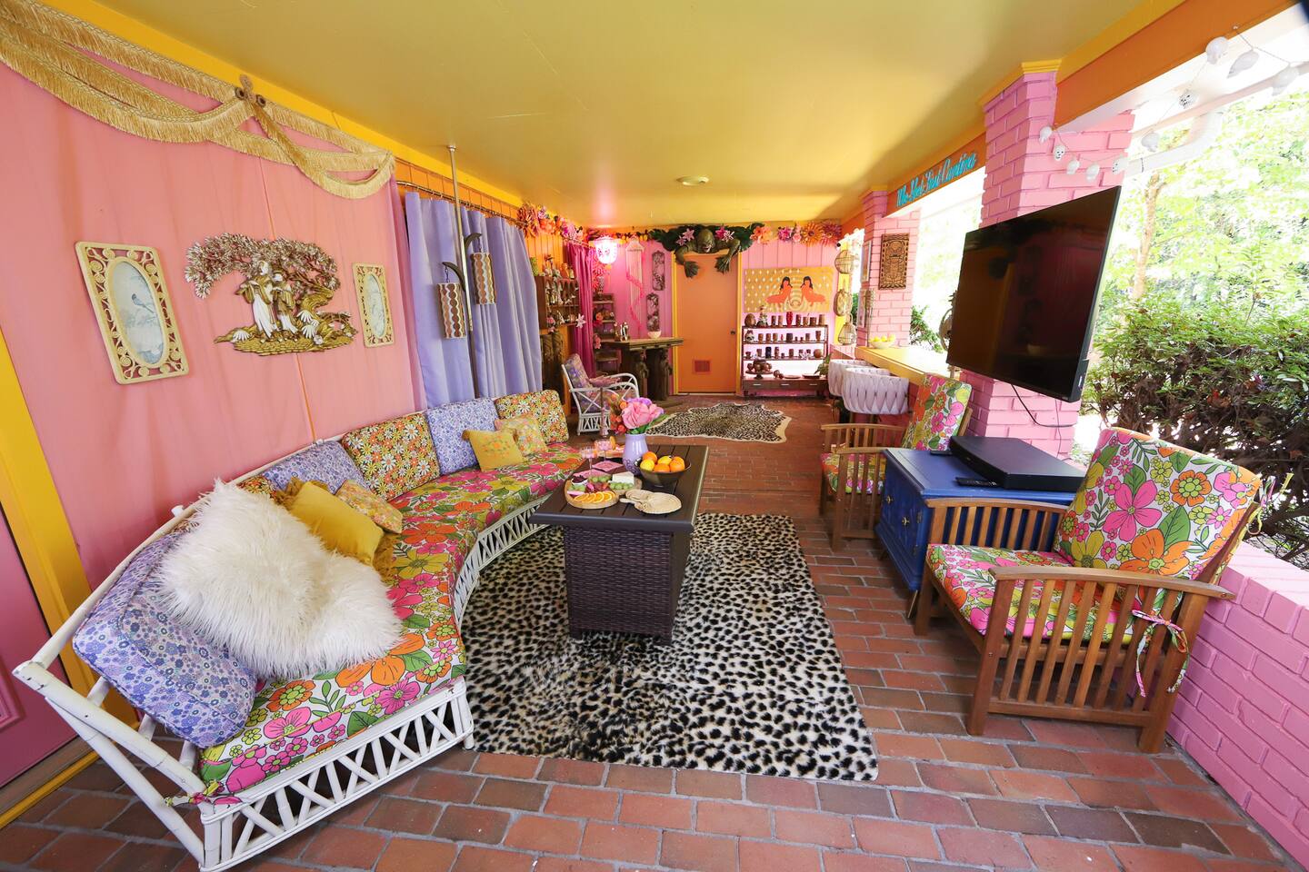 Tropical patio lounge with floral cushions, string lights, and pink brick walls